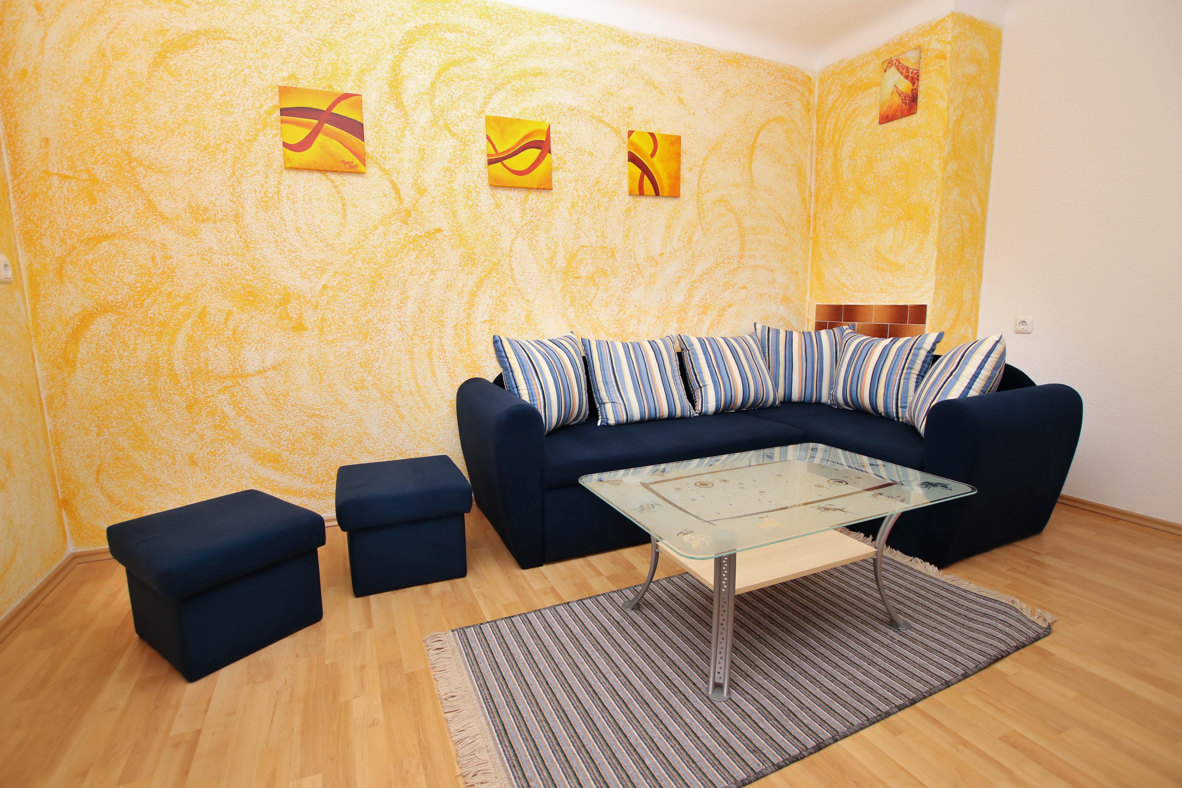 Das in Orange gestrichene Wohnzimmer mit baluer Couch und gestreiften Zierkissen.
