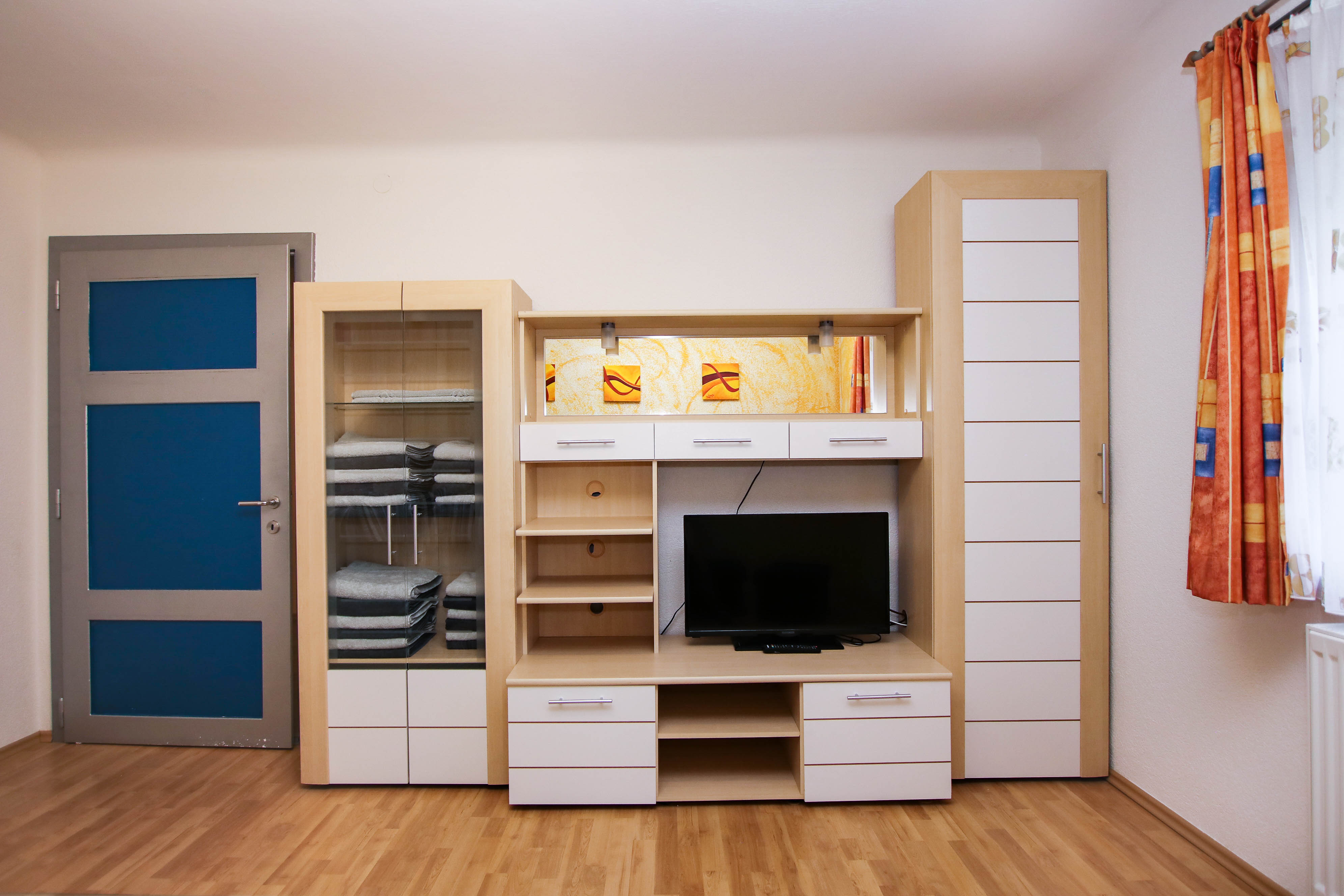 Die Wohnwand im Wohnzimmer mit mehreren Schubladen und Kästen sowie einem Fernseher.