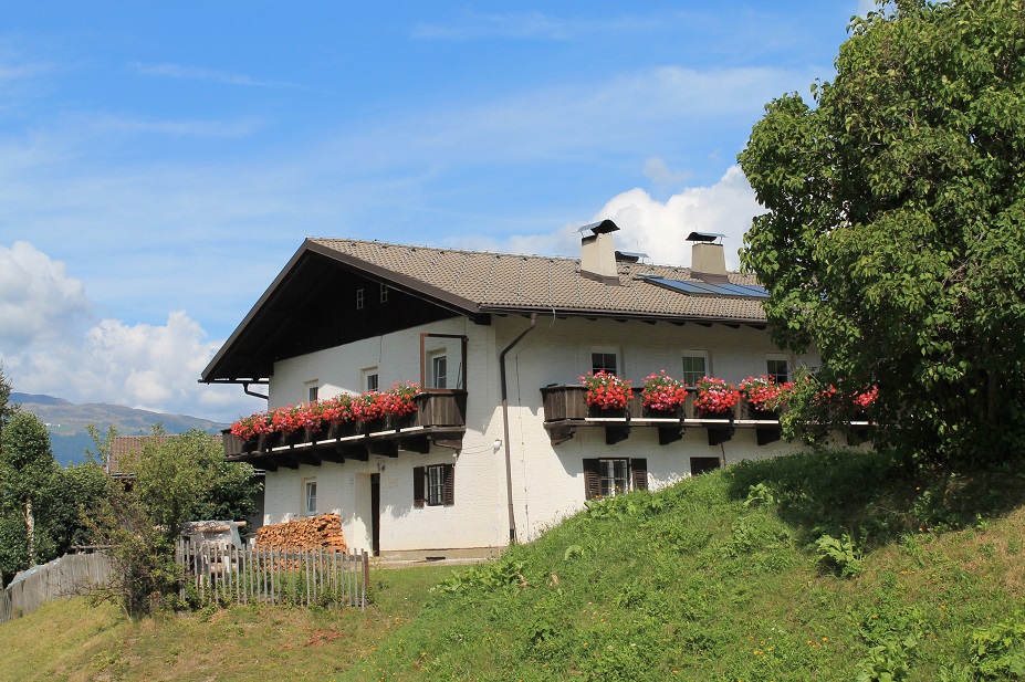 Man sieht ein Haus mit einem Balkon und Blumen darauf.