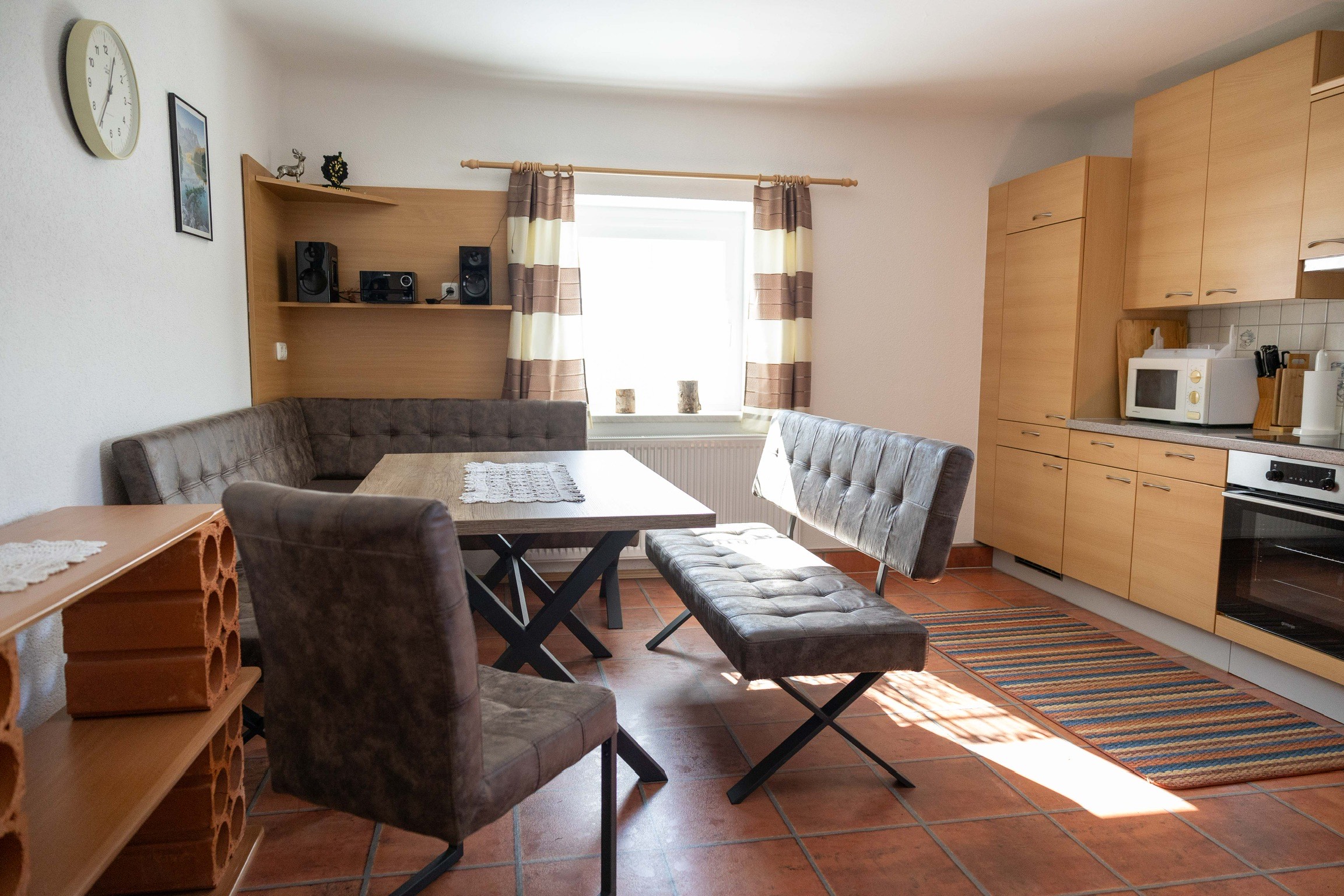 Die Küche im Apartment Klammer mit gemütlicher Sitzecke in brauner Lederoptik und Blick nach Süden beim Fenster hinaus.